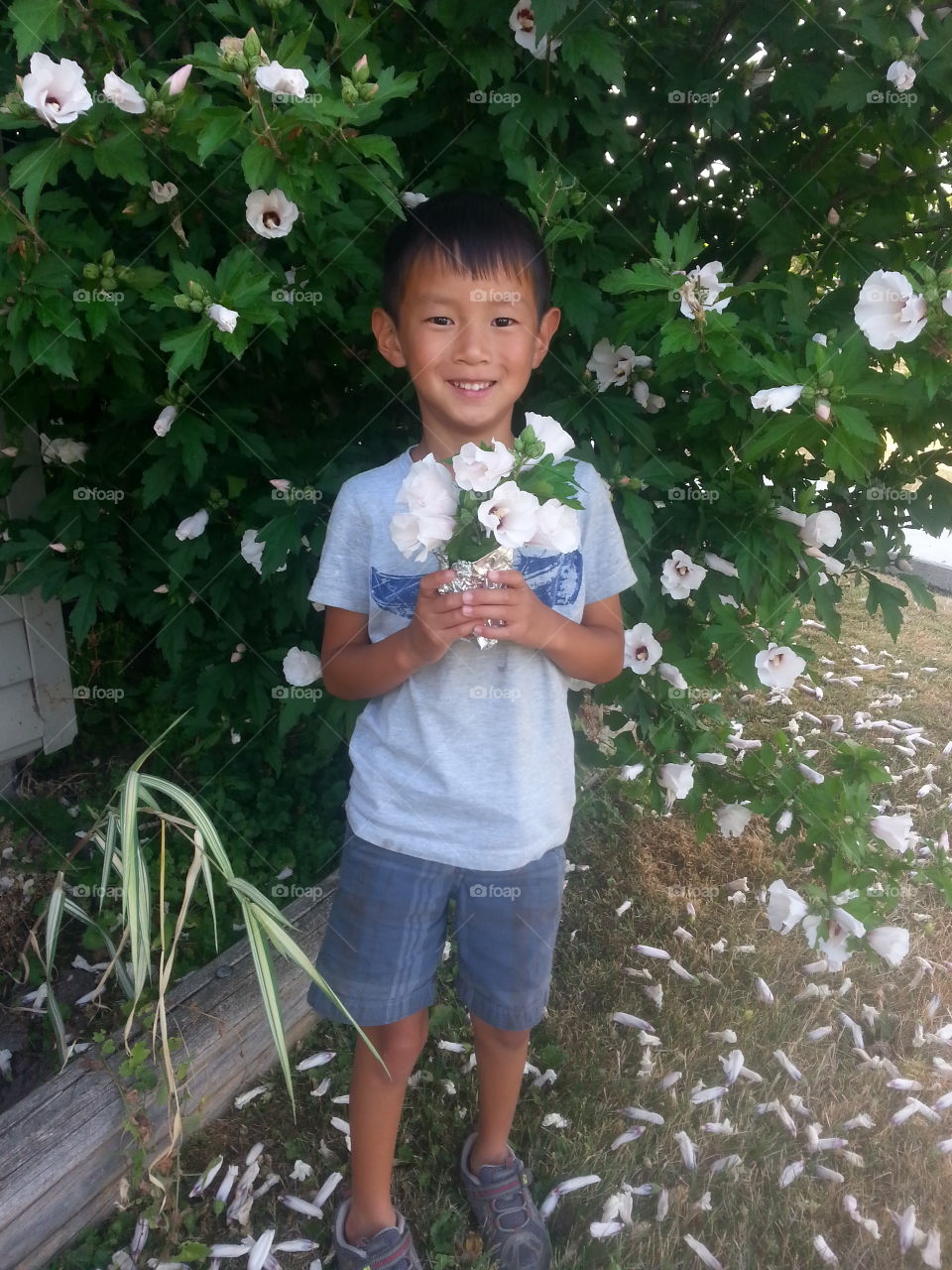Cute asian boy holding flower bouquet near tree