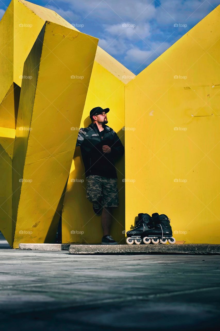 Man with his skates standing by the yellow wall