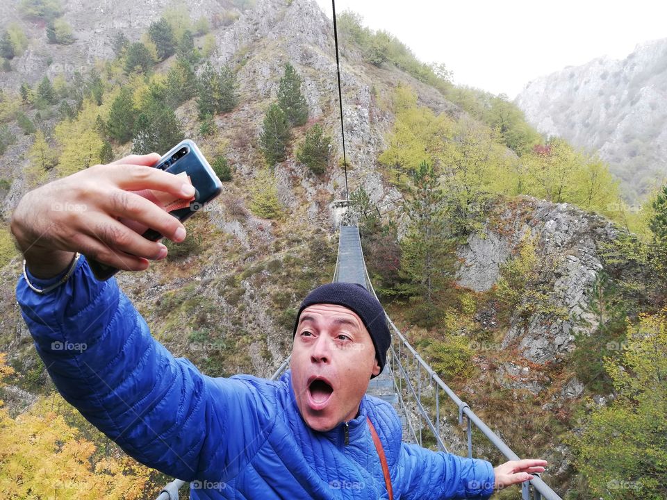 Man makes selfie with expression of fear on the Tibetan bridge