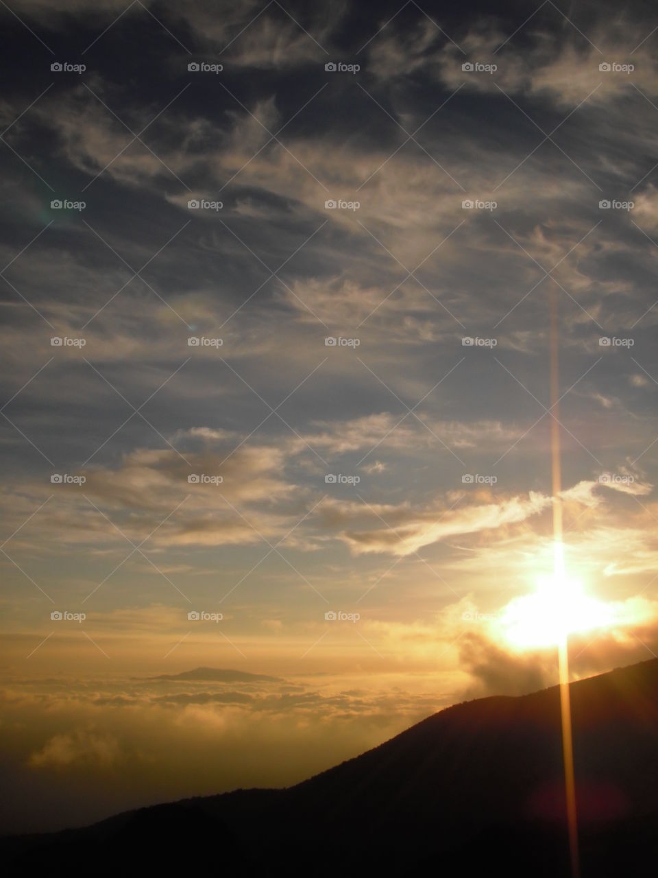 View of the sun setting into the clouds from Mauna Kea. 