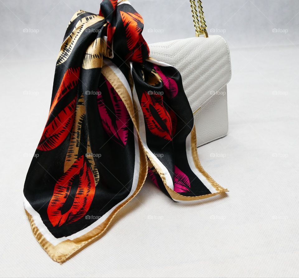 A White Bag Emblishes With A Square Scarf