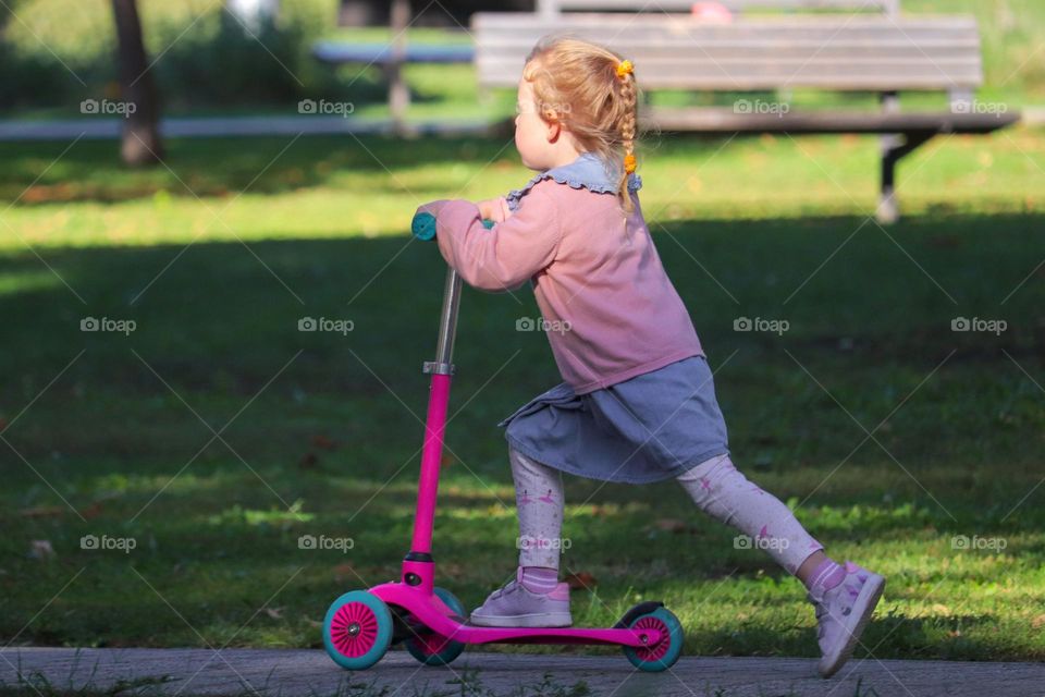 A girl on a scooter in the park