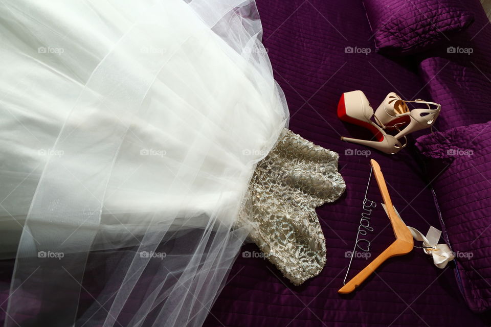 Bridal dress and shoes. White bride dress lying on bed and shoes by its side. Wedding day starts
