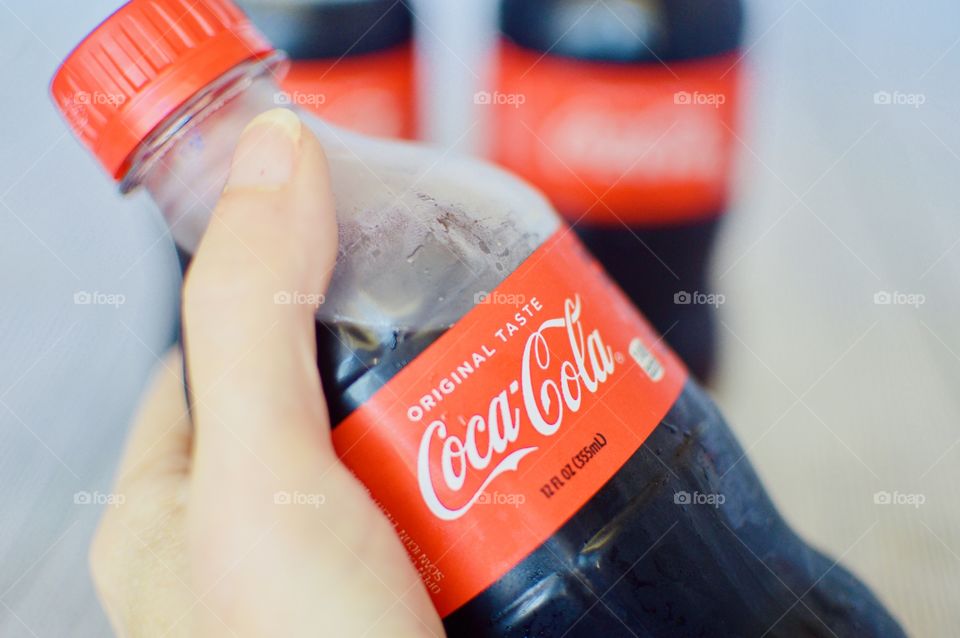 Three plastic bottles of Coca-Cola on a white rustic background
