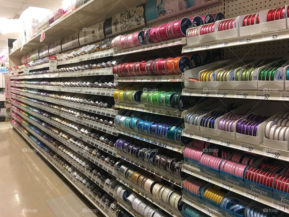 Rows of ribbon organized by color at a craft store. 