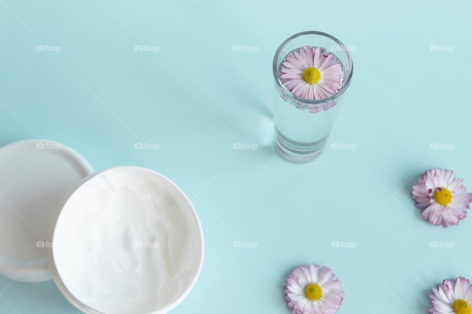 Jars with cosmetic products, beauty cosmetics in a white jar with cream and water with fragrant flowers.