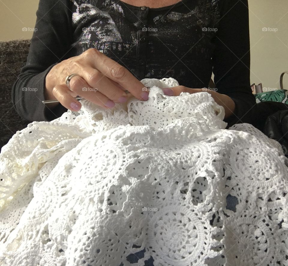 Woman crocheting white lace cotton tablecloth closeup hands handiwork
