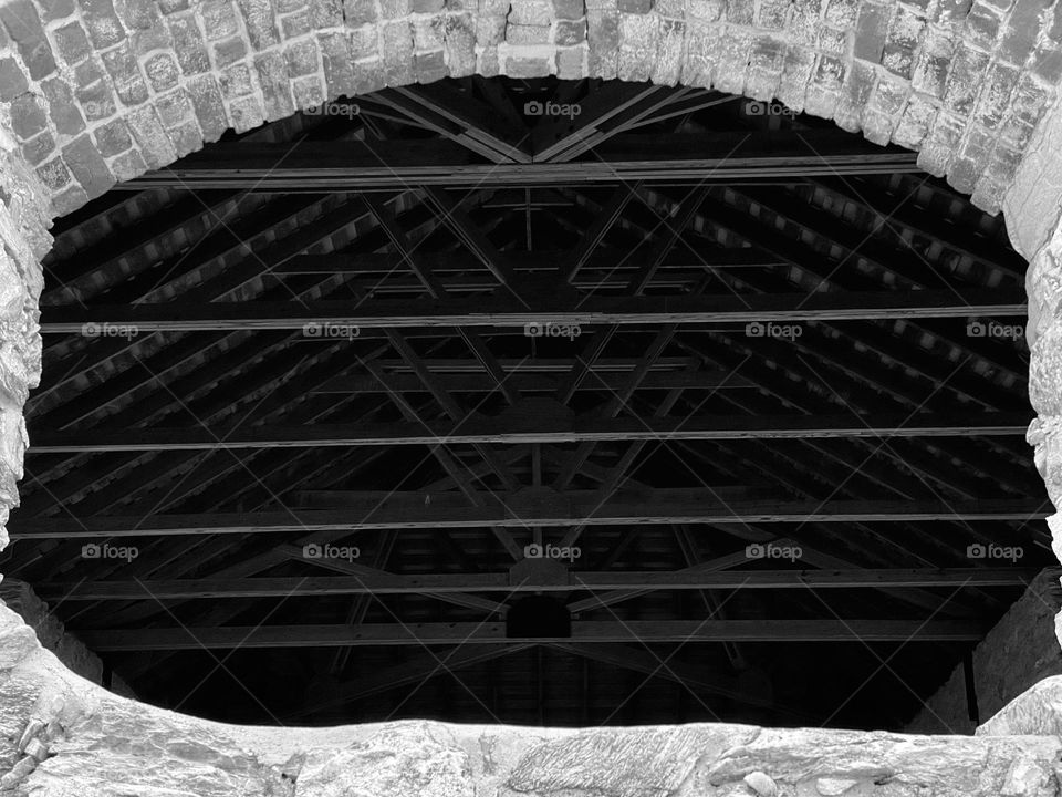 Looking through a window at the rafters of an old barn