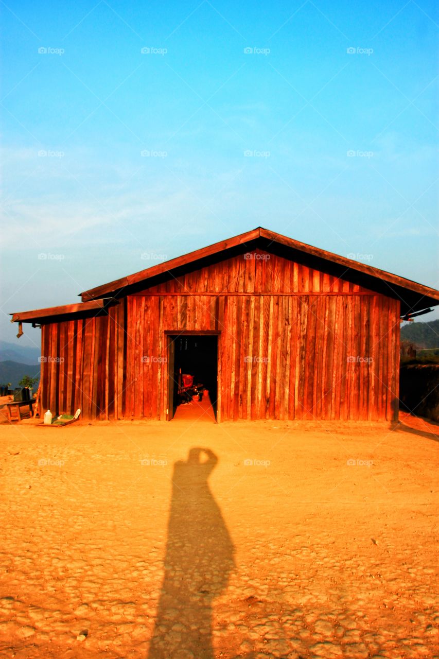 The shadow of a photographer standing on a wooden house in the outback in the mountains  He was standing to shoot in the evening when the light was beautiful.