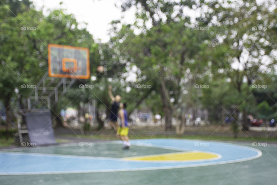 Blurry image teens playing basketball in the morning at BangYai Park , Nonthaburi in Thailand.