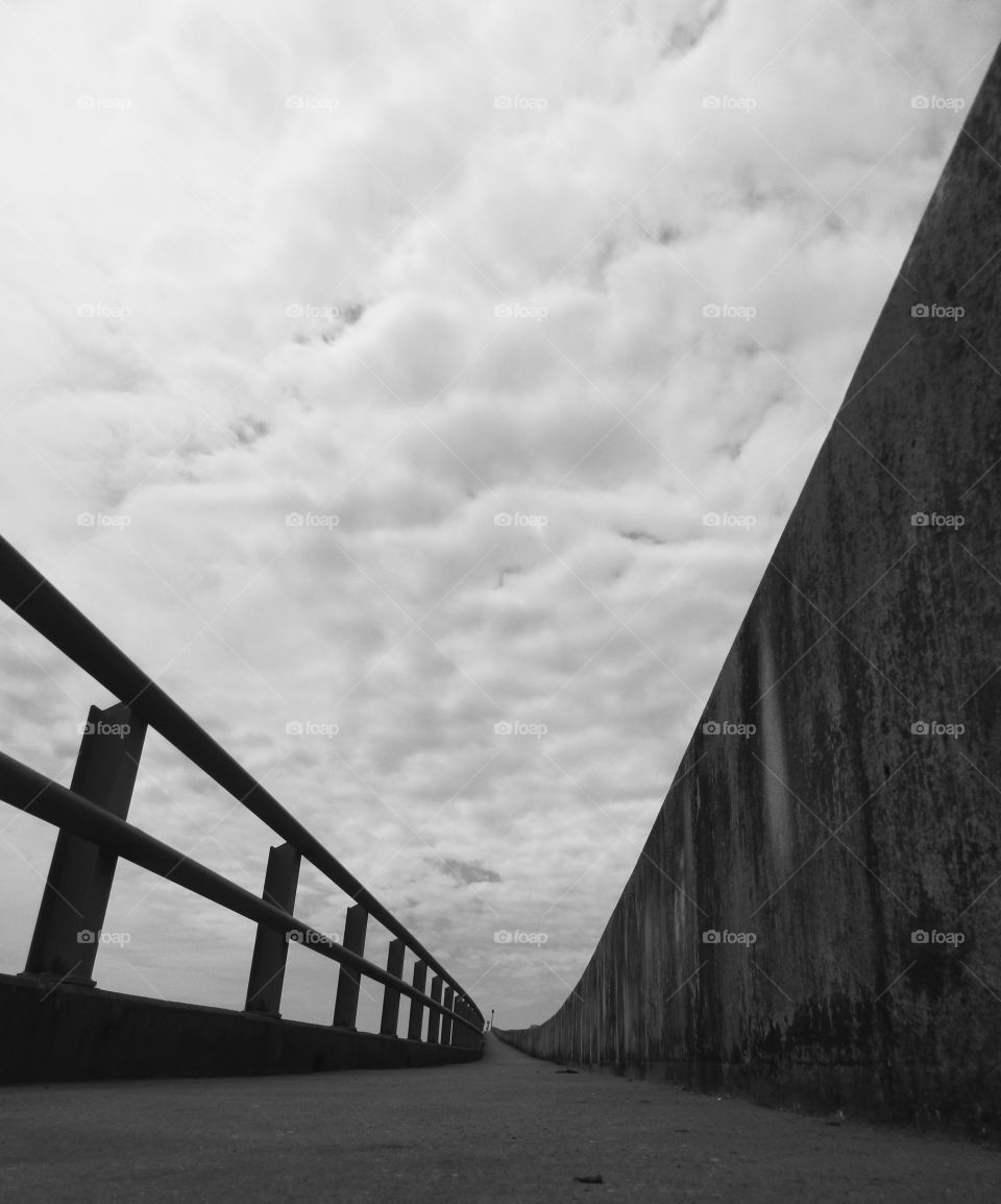 Bridge over troubled waters. This bridge is at the intersection of the bay and the ocean looking up to the sky and puffy clouds!