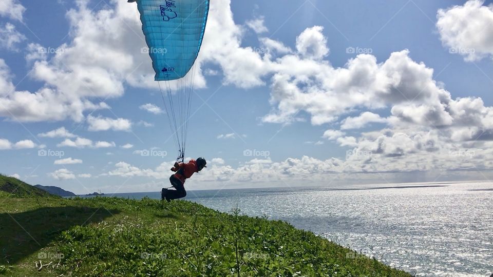 Man paragliding by the beach