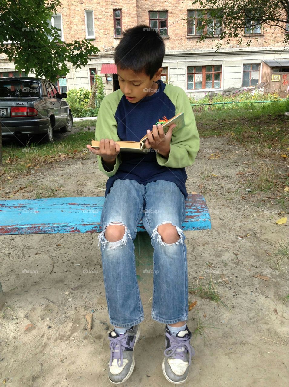 Portrait of a boy sitting on bench reading book