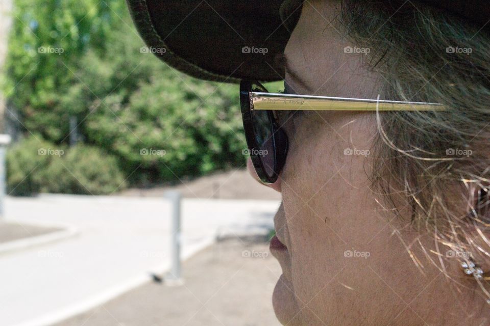 Middle aged blond woman closeup headshot profile wearing leather cowboy hat at sunglasses sunnies