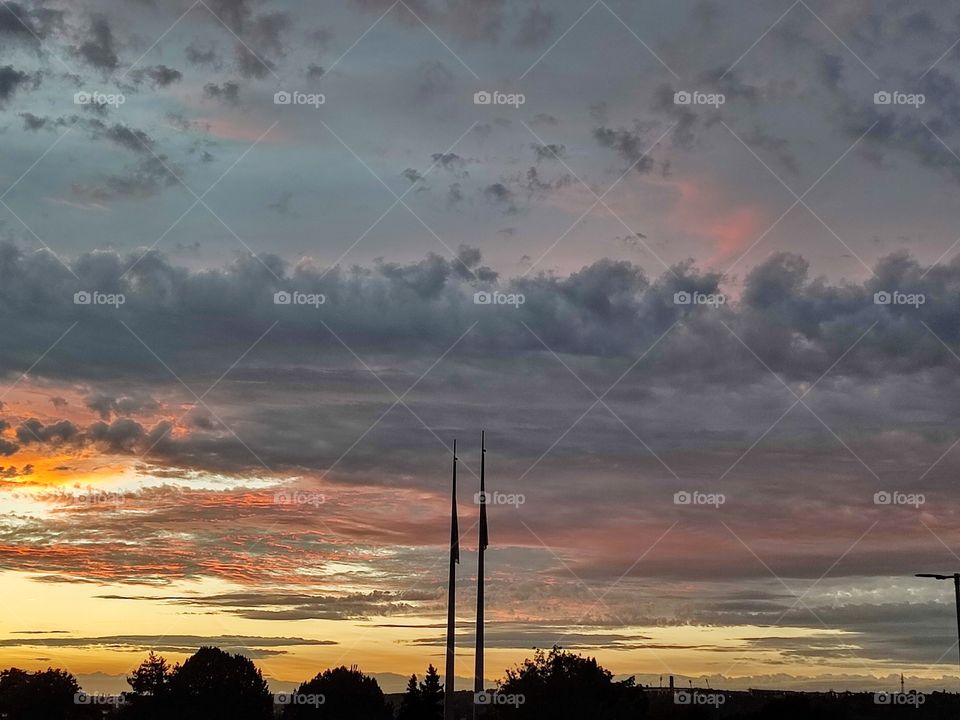 Two parallel poles against a cloudy sky at dusk.