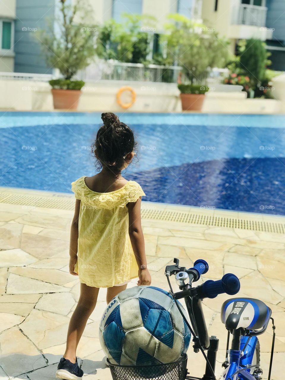 A girl stand  and looking towards swinging pool in yellow a summer outfits.