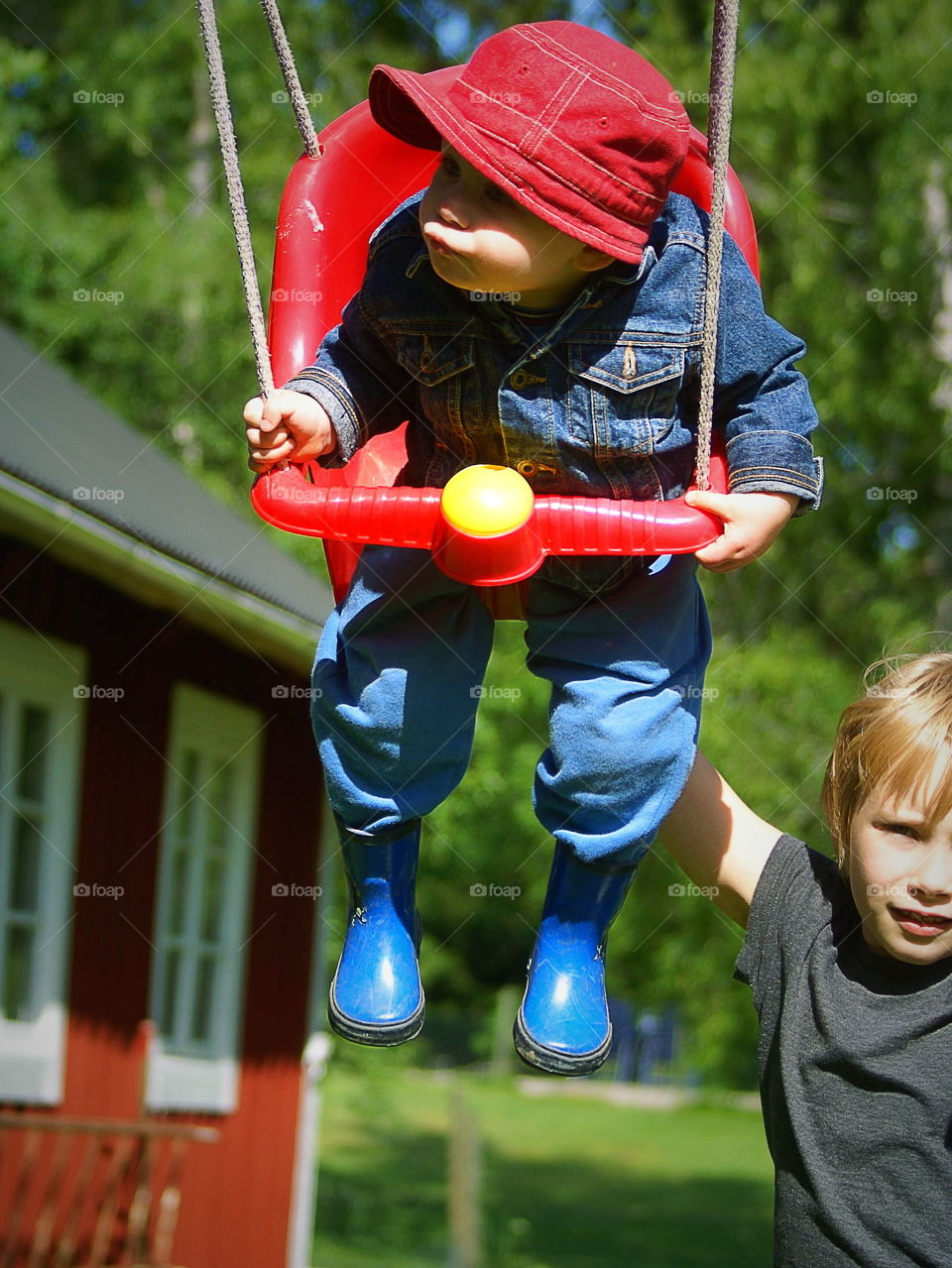 Toddler swinger and big sister helps pushing
