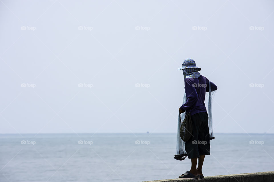 Man holding fishing nets  Background sea and sky.