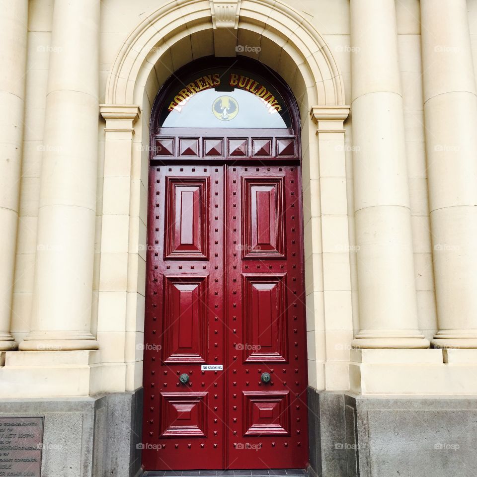 Maroon coloured door with panels and columns