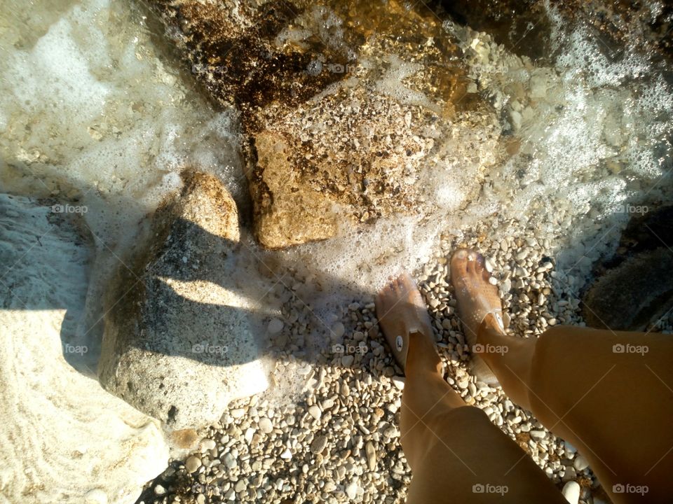 legs female on the sea stones shore