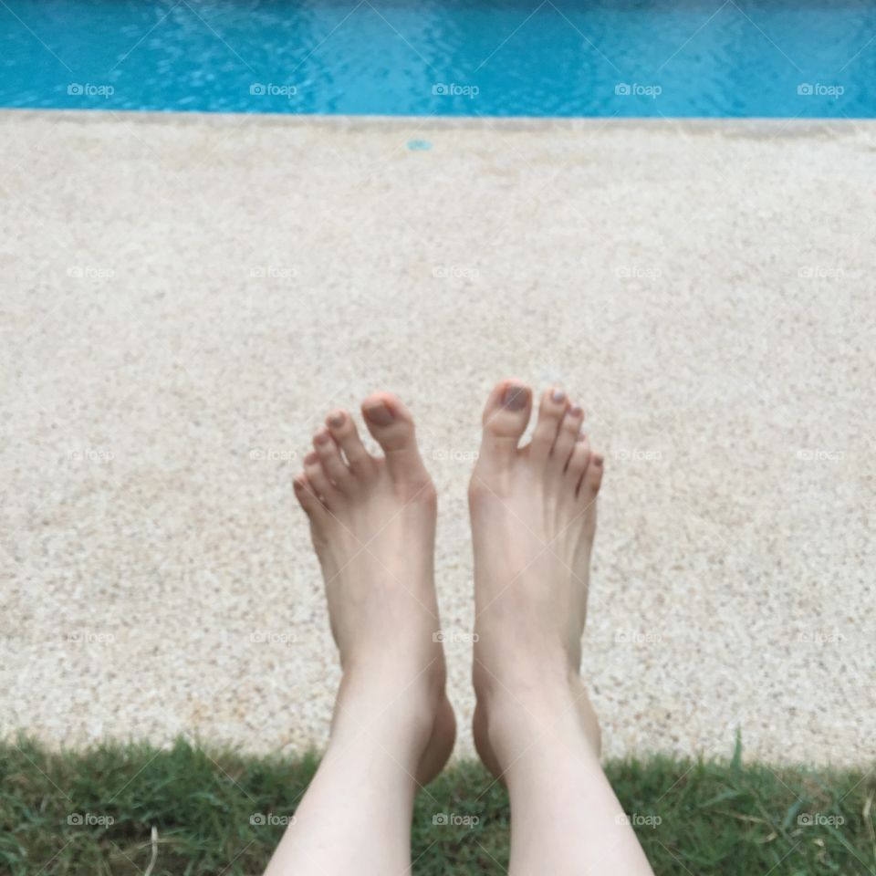 View of bare female feet at swimming pool side great for any use.