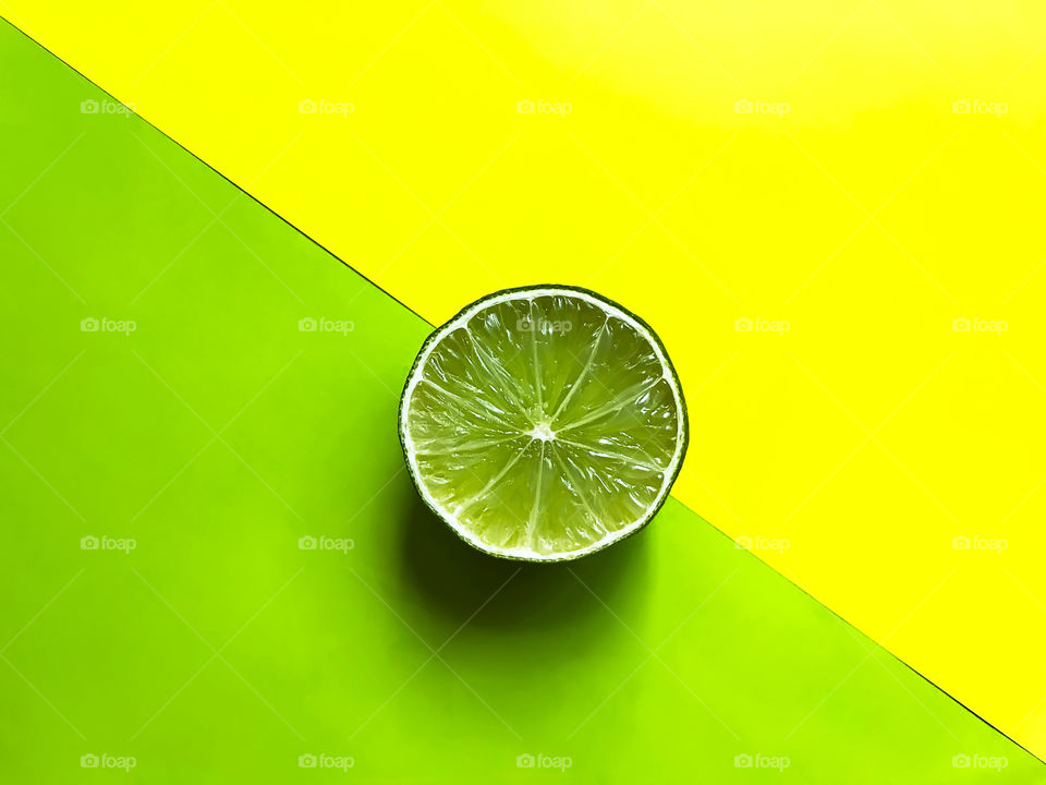 Slice of lime on yellow and green background 