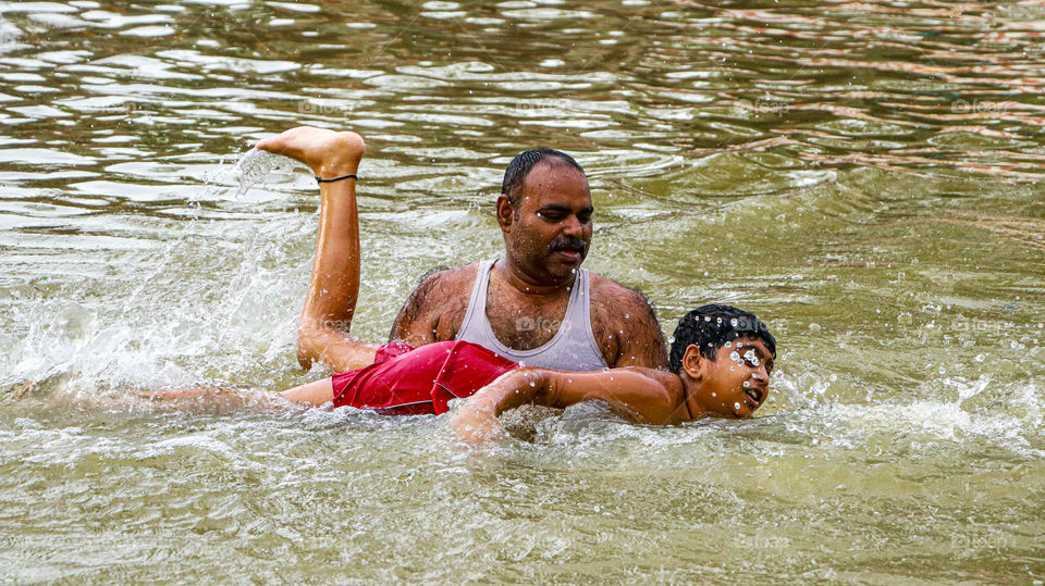 A splash stort of a dad who was teaching swimming to his son..