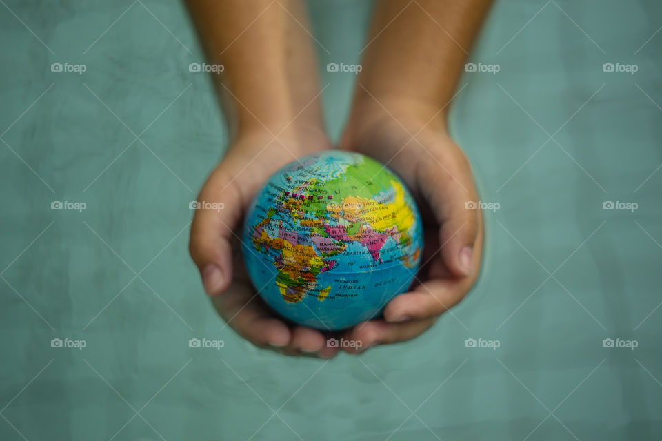 overhead looking down on hands holding world sphere, showing Africa, Europe and Asia continents