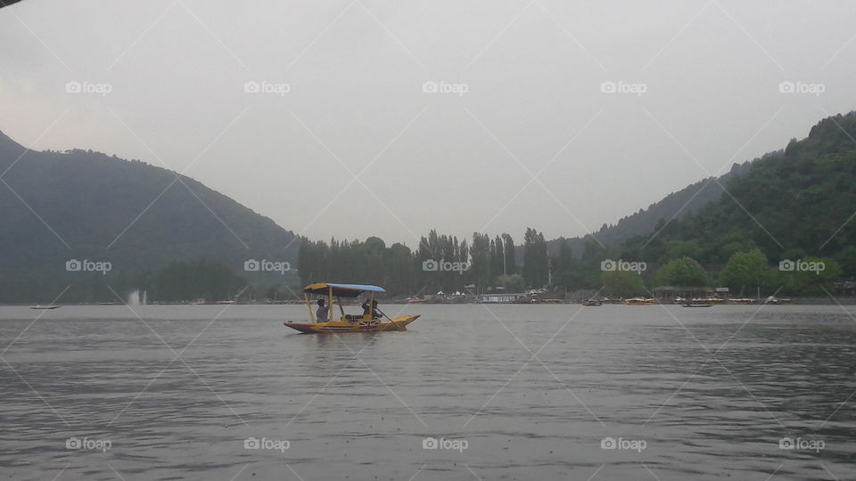 A boatman rows his boat called "Shikara" in the middle of Dal Lake waters  towards his Big Boat in World famous Dal Lake in Srinagar KASHMIR (Summer 2019)