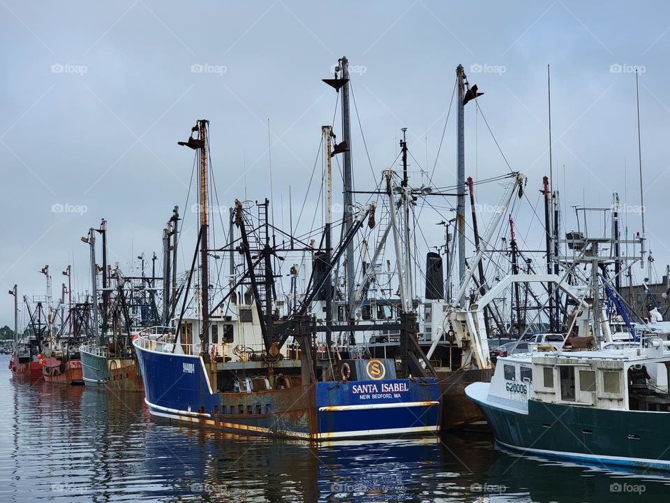 Old Fishing Boats Docked at a Marina with Gray Cloudy Sky in the Background