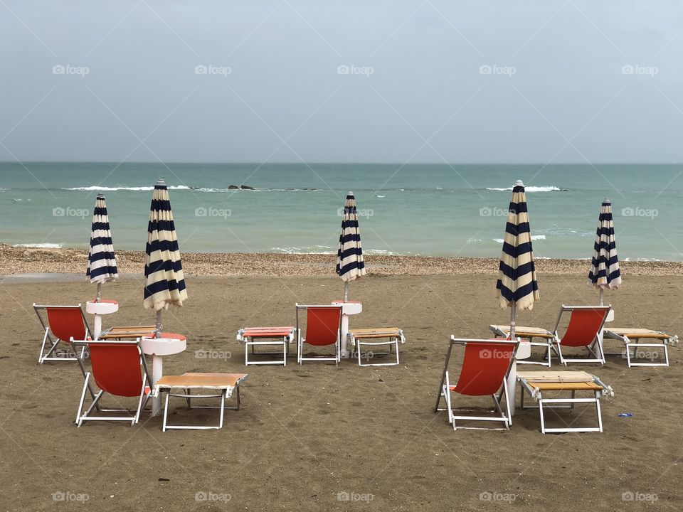 Rainy september day view over closed umbrellas and deck chairs on the beach