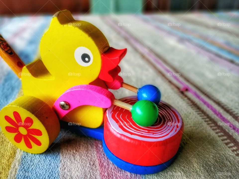Beautiful Hand made wooden toy duck beating Red color drum on carpet.