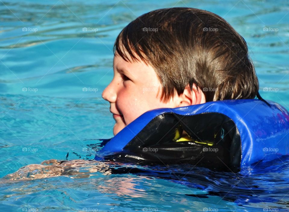 Happy Young Swimmer. Young Boy Learning To Swim In A Pool
