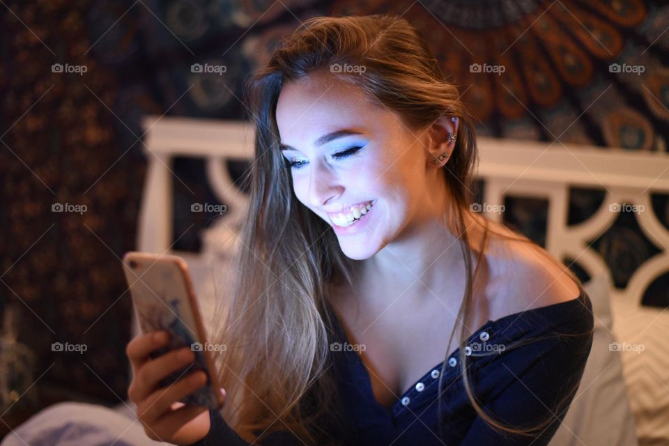 Pretty young woman smiling, looking at MobilePhone