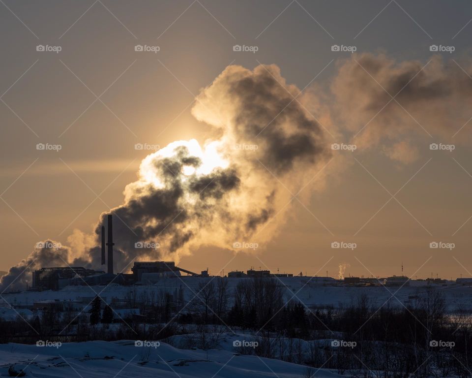 Sun illuminating through the smoke of a foundry, winter, horizontal 