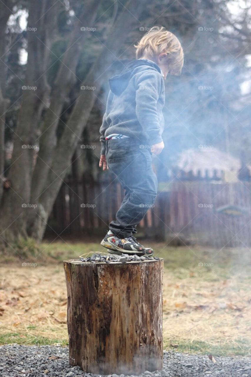 Boy standing on tree stump