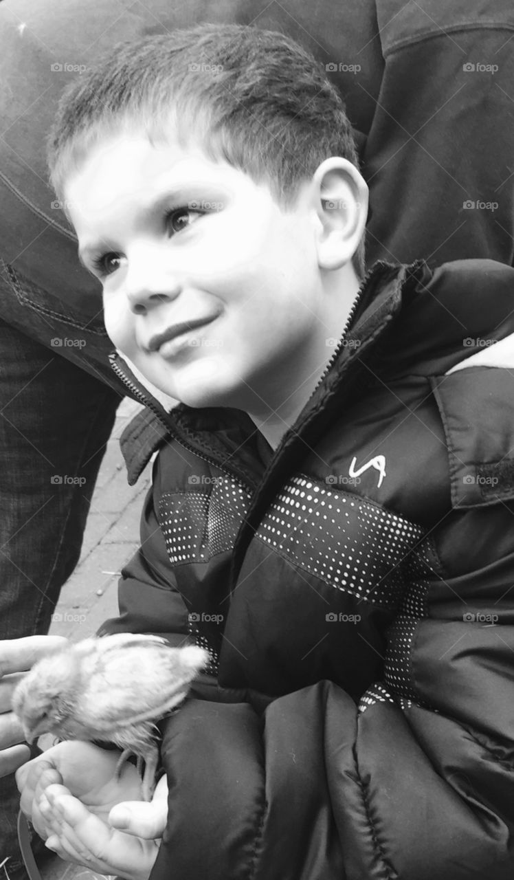 Black and white close-up of a Little boy holding a chick