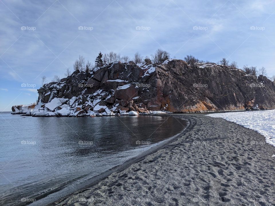 moody sandy beach with snow and ice and beautiful blue skies