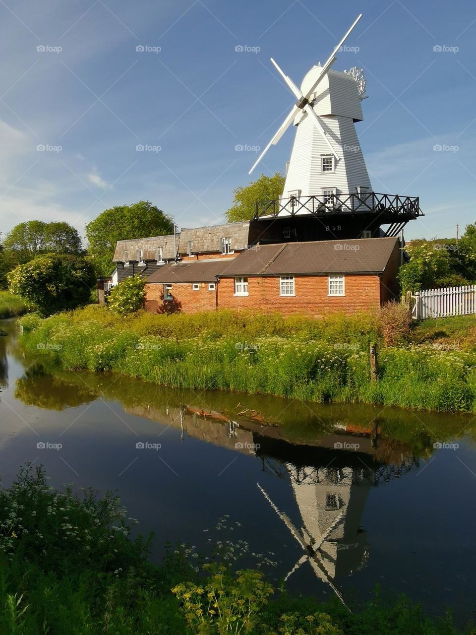 Beautiful reflection of the old mill in the river. Countryside. Sunny summer day.