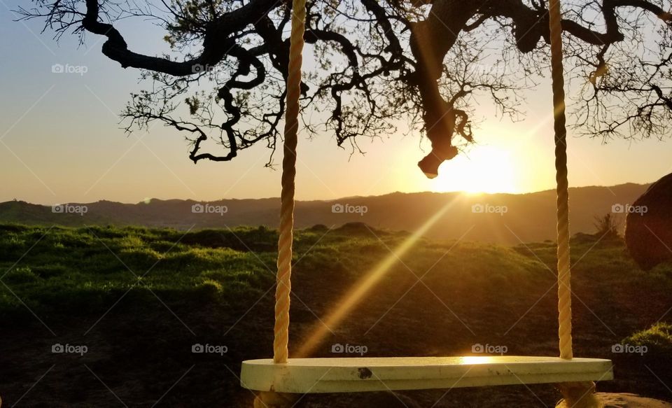 A yellow swing reflects the sunset light 