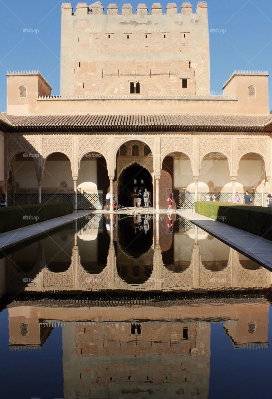 A stunning courtyard with a gorgeous reflection portraying the harmonious architectural design of the Alhambra castle.