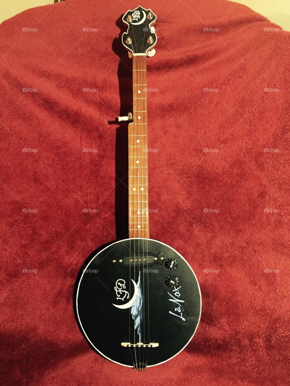 A handcrafted wooden banjo that my husband made showing off a black body with a moon design on it and an oak wood neck on it. 