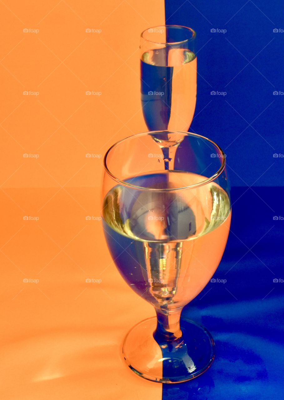 Blue and orange background reflecting into two glasses of water