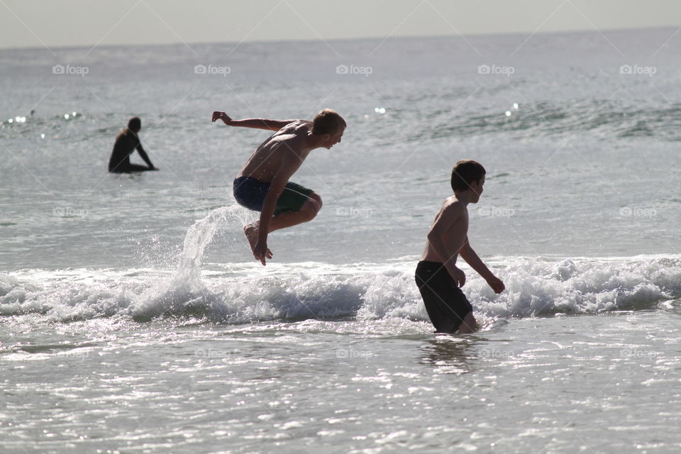 Boys wave jumping in the surf 