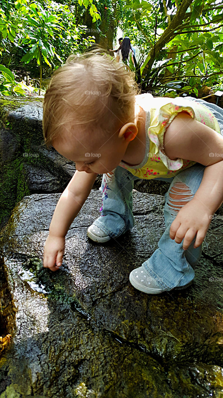 Cute little girl playing on wet rock