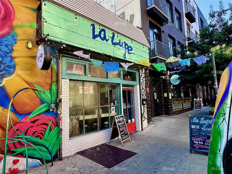 This is the popular club restaurant “La Lupe” on “Jefferson St” off “Broadway” in “Bushwick”, Brooklyn at the end of a large art mural celebrating the Latin culture. 2024. Hypnotic Productions