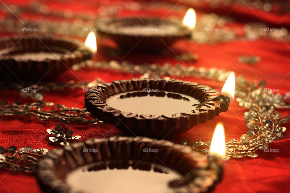 Indian  festival Diwali diya oil lamp on red satin background with bokeh blur