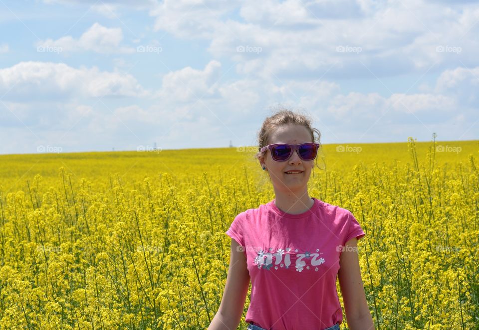 beautiful girl on a yellow flowers rapeseed field background