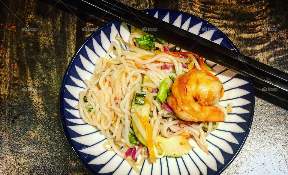 Asian noodles with shrimp and chopsticks on a pretty plate 