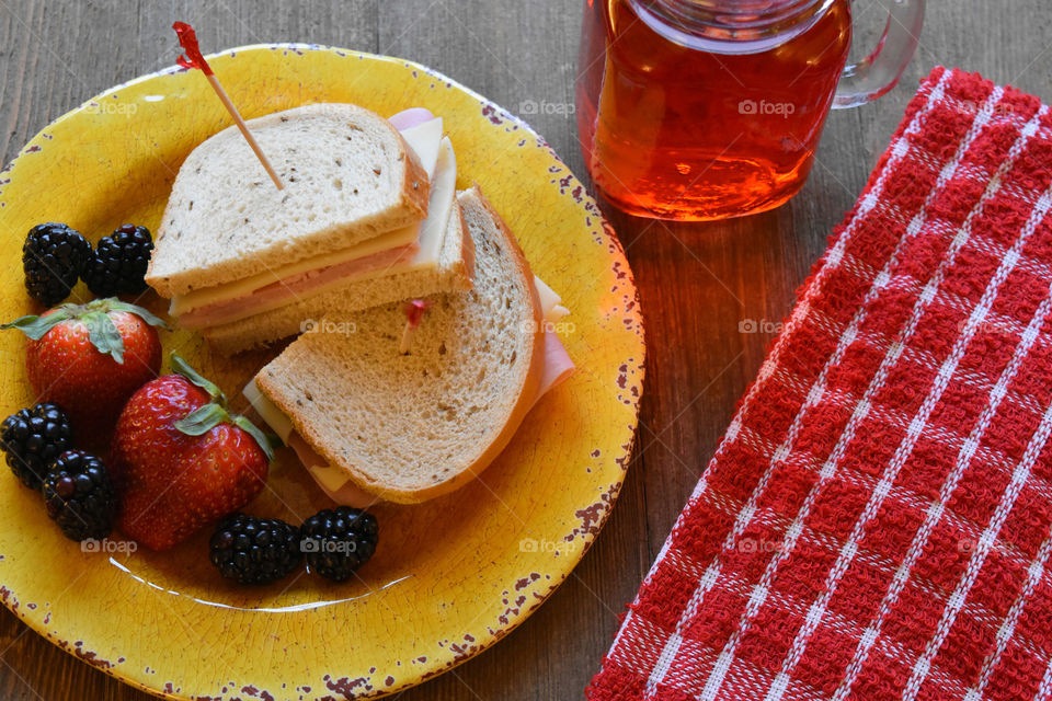 Ham and cheese sandwich with fruit and a glass of juice